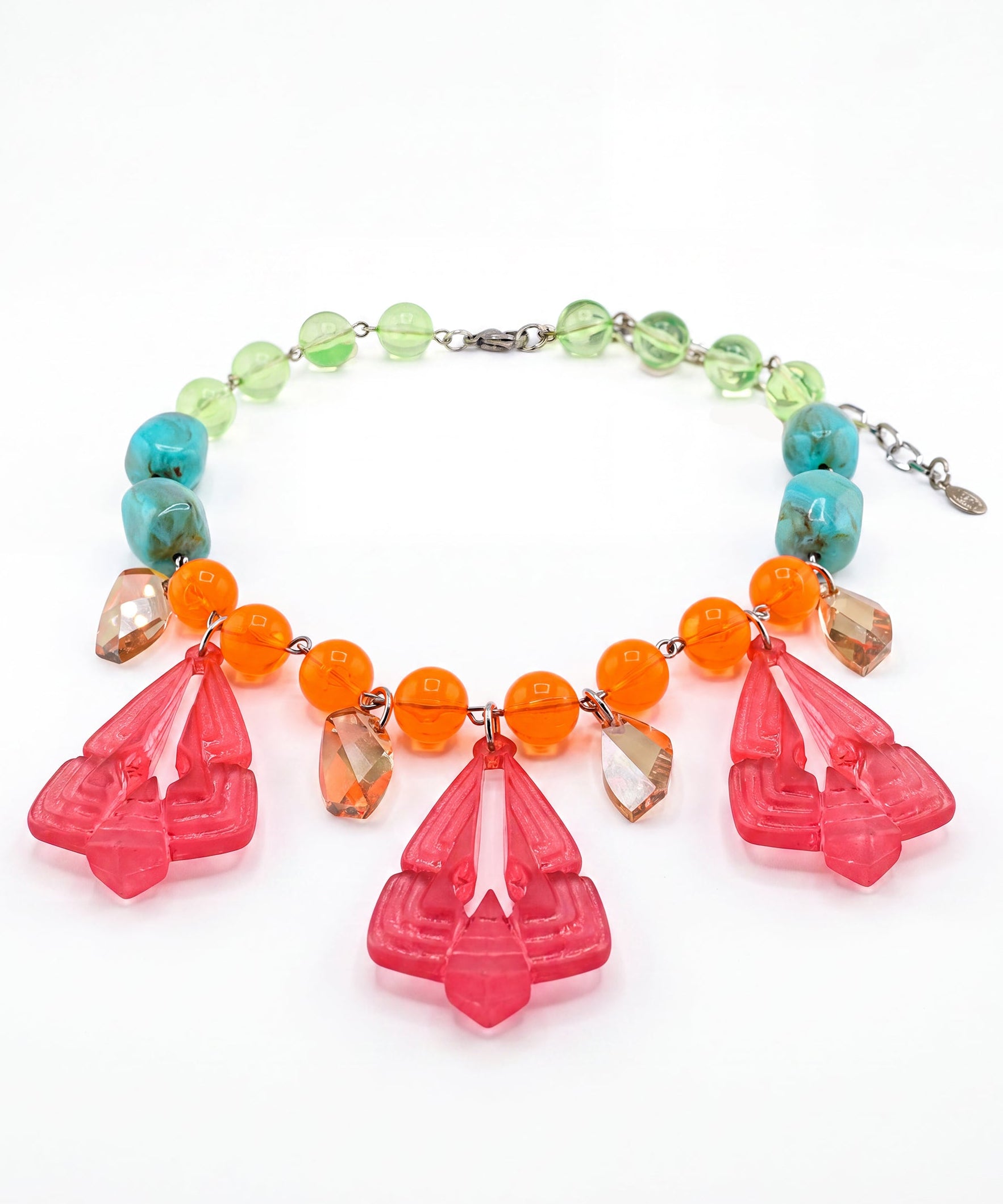 A vibrant statement necklace featuring large, translucent pink Art Deco style teardrop pendants, accented by bright orange beads, turquoise blue beads, and light green beads on a silver-tone chain.