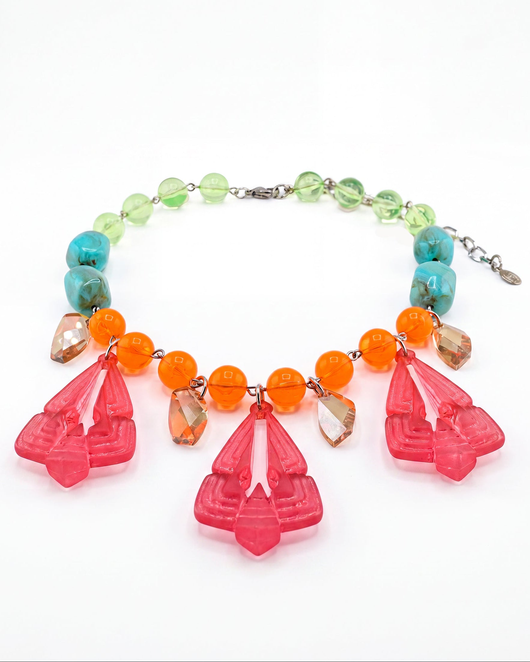 A vibrant statement necklace featuring large, translucent pink Art Deco style teardrop pendants, accented by bright orange beads, turquoise blue beads, and light green beads on a silver-tone chain.